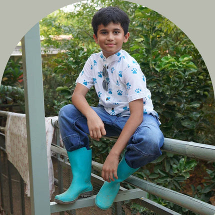 Boy in blue boots and white organic cotton shirt with blue paw prints, Dhonk Craft, outdoors