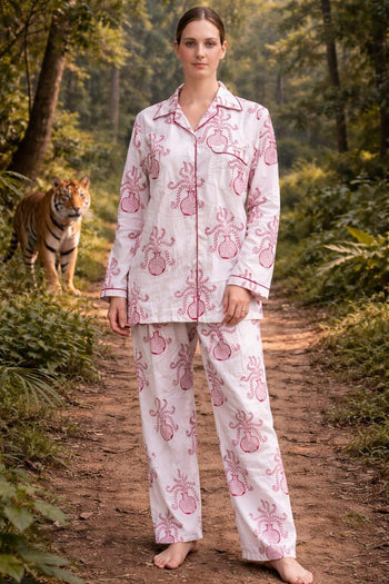Woman in handcrafted organic cotton pajamas with pink floral print, standing on forest path with a tiger in the background, Dhonk Craft ethical clothing.