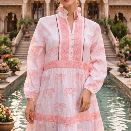 Woman wearing handcrafted pink and white cotton dress with tiger print, standing by palace pool
