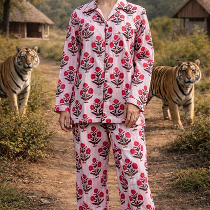 Woman in pink floral organic cotton pajamas by Dhonk Craft, standing outdoors with tigers nearby.