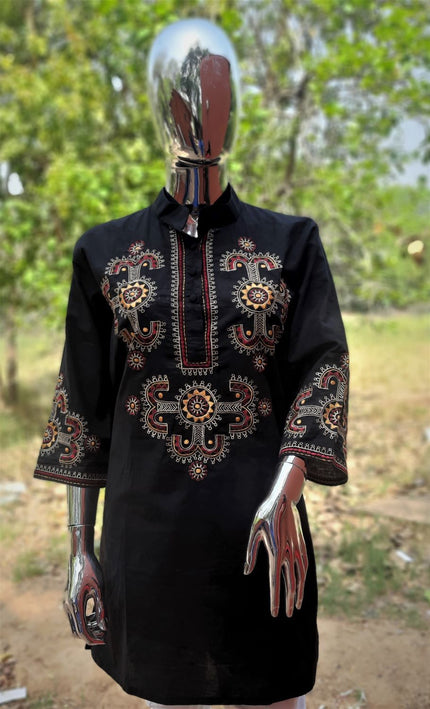 A black embroidered tunic displayed on a mannequin, featuring intricate traditional craftsmanship.