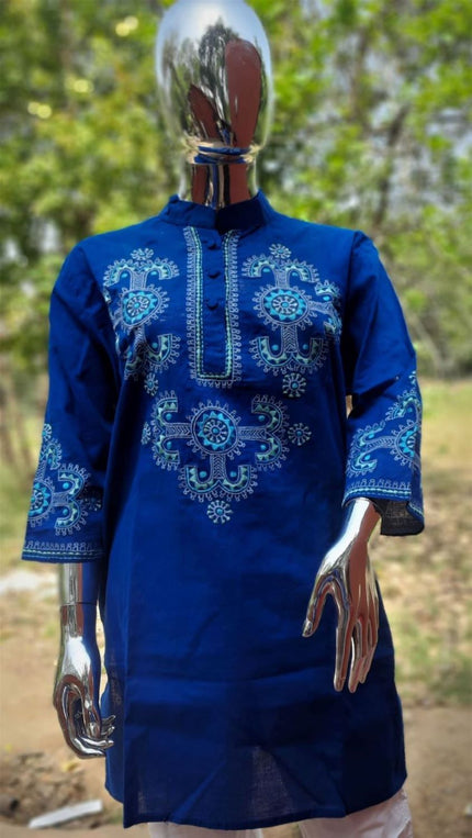 A blue embroidered tunic displayed on a mannequin, featuring geometric patterns and traditional craftsmanship.