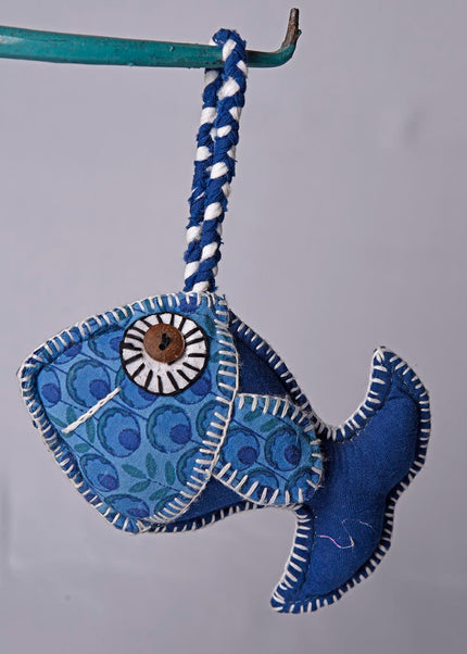 A blue fabric fish toy with a patterned body and a fringed tail, designed for hanging.