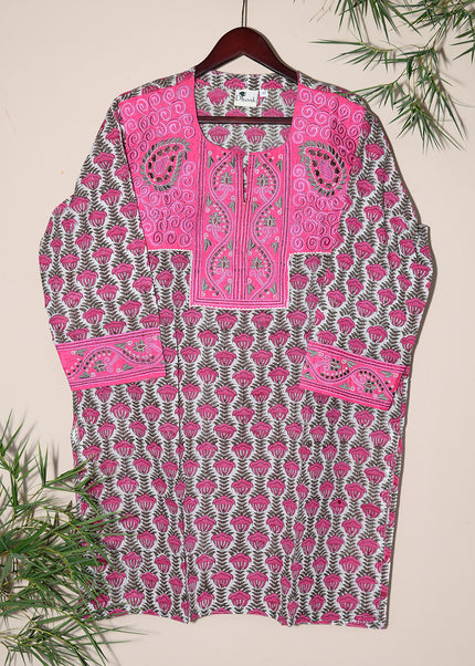 A pink and black embroidered hand block print tunic hanging on a hanger with a decorative background.