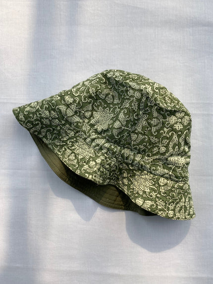 A green hand block printed cotton hat laid flat on a white surface.