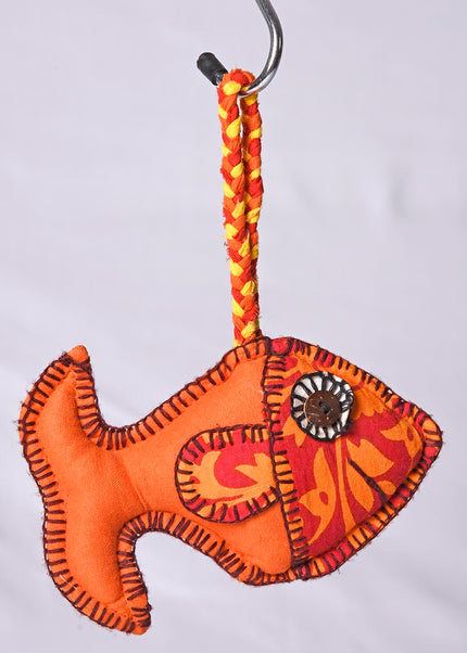 A handmade fabric toy resembling a fish, primarily orange with additional colors, designed as a hanging decoration or plush toy.