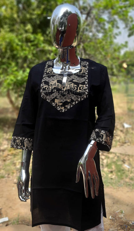 A black traditional Kurta with patch work design displayed on a mannequin against a backdrop of trees.