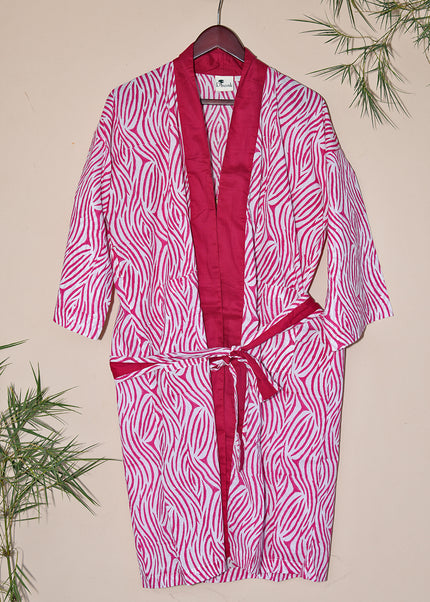 A pink robe with black and white zebra stripes, displayed on a hanger with a belt attached.