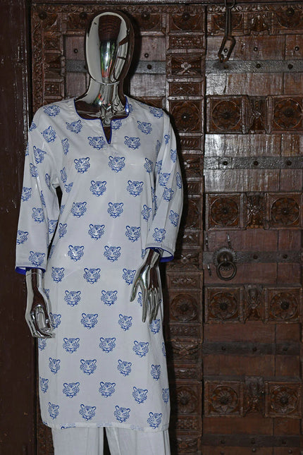 Handcrafted white kurta with blue tiger print by Dhonk Craft, displayed on mannequin, rustic wooden door backdrop.